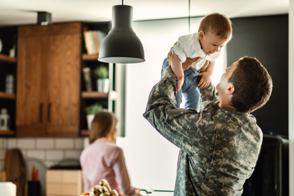 National guard member holding his child with his wife nearby.