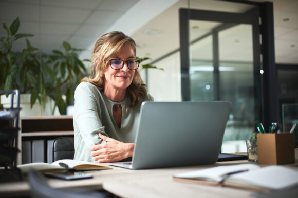 Middle-aged woman using a laptop, reviewing TSP military retirement options.