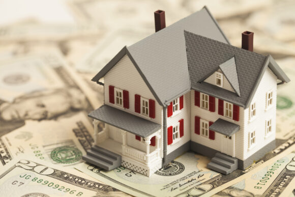 Model house sitting on dollar bills.